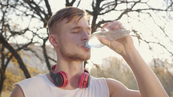 Close-up Portrait of Handsome Caucasian Athletic Man Drinking Water in Sunlight