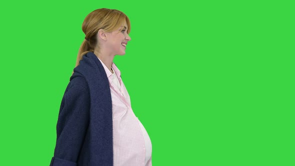 Beautiful Happy Pregnant Woman Walking After Shopping on a Green Screen, Chroma Key.