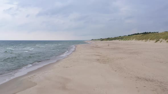 AERIAL: Flying Forward on a Cloudy Evening Over Sandy Beach and Sea Shore