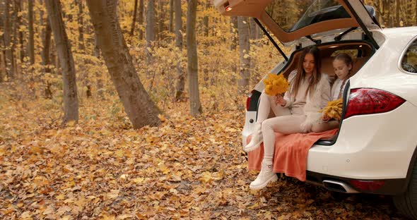 Mother and Daughter Sitting in a Car Trunk