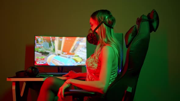 Young Gamer Woman in a Black Respirator Sitting By the PC and About To Play a Shooter Game