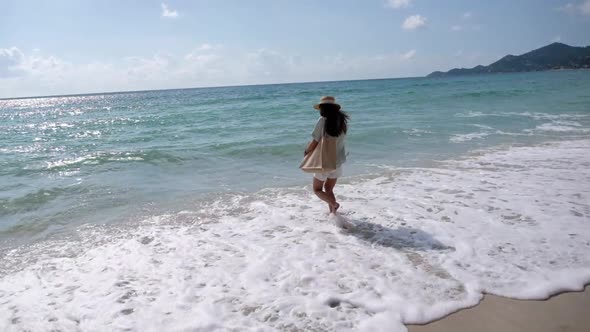 Slow motion of a beautiful young asian woman walking and playing with the sea