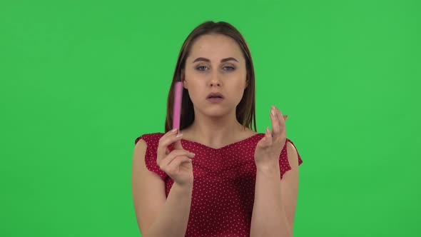 Portrait of Tender Girl in Red Dress Is Making Herself Manicure with Pink Nail File. Green Screen