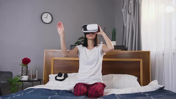 Woman in Sleepwear Sitting on Bed and Working on Virtual Screen Applying Augmented Reality Goggles