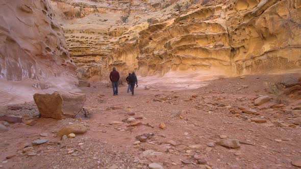 View of 3 people hiking through Crack Canyon in Utah