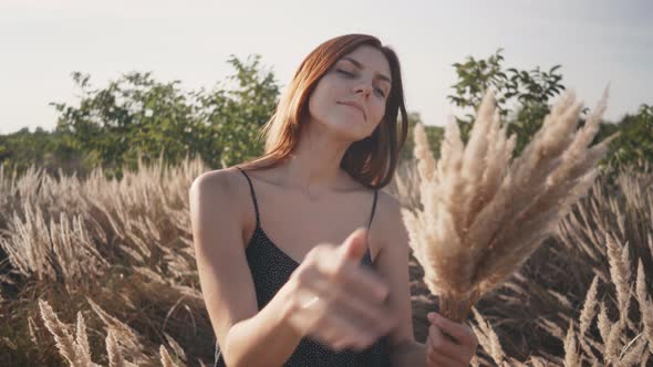 Beautiful Young Woman Walks in the Field Collects a Bouquet of Flowers and Spikelets