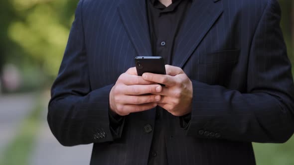 Close Up Male Hands Unknown Man in Black Formal Suit Hold Smartphone Chatting in Social Media Use