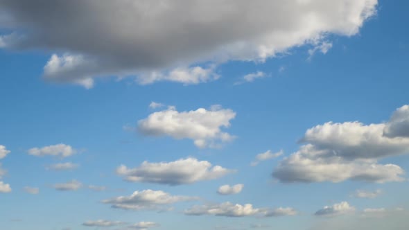 Time lapse footage of fast moving white clouds on blue clear sky.