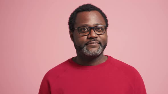 Positive adult African man looking around and showing silence gesture