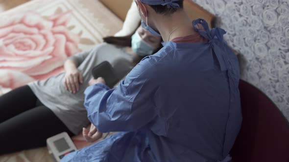 The doctor measures the patient's blood pressure at home.