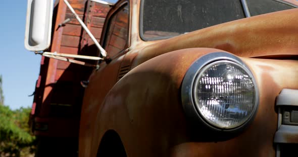 Pan and tilt down along the front of an old rusty vintage truck fender with glass headlight and gril