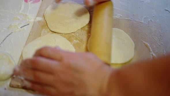 Female Hands Roll Out Round Pieces of Dough with a Rolling Pin for Pies