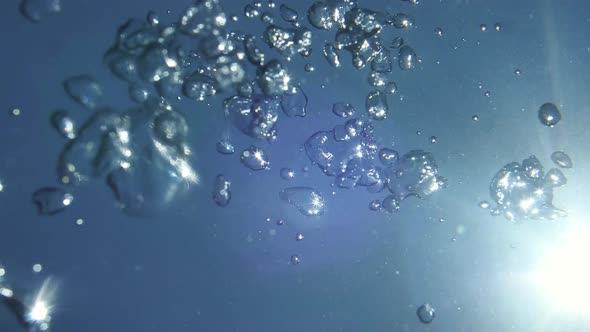 Natural Light Rays in Clean Water Shining Through the Air's Glittering and Moving Bubbles