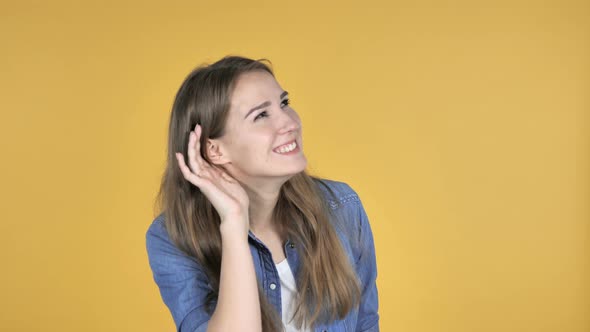 Pretty Woman Listening Secret Standing Isolated on Yellow Background