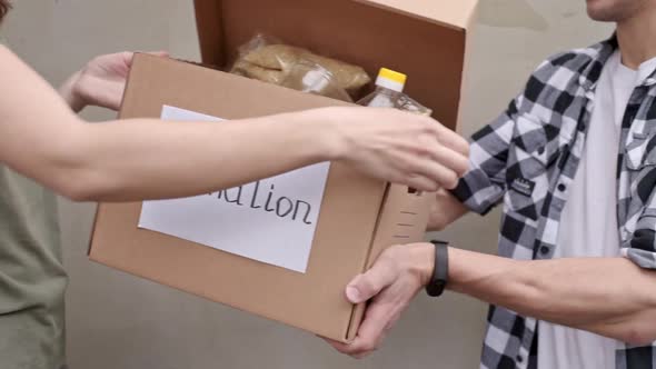 Man Give Donation Box to Woman Volunteer