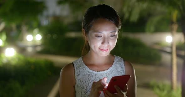 Woman use of mobile phone at outdoor in the evening