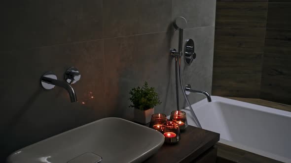 Romantic Candlelit Bathroom with Red Burning Candles on the Vanity, Tiled Walls and Fitted Bathtub