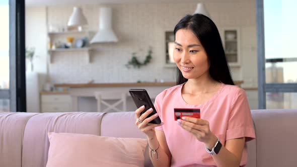 An Attractive Young Asian Woman is Using a Smartphone for Shopping Online