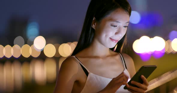 Young Woman use of mobile phone in city at night