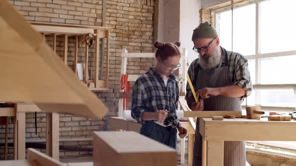 Aged Craftsman with Teenage Girl in Workshop