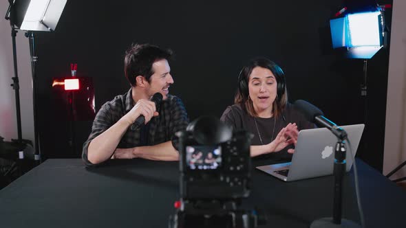 Happy male and female bloggers recording video on camera in studio