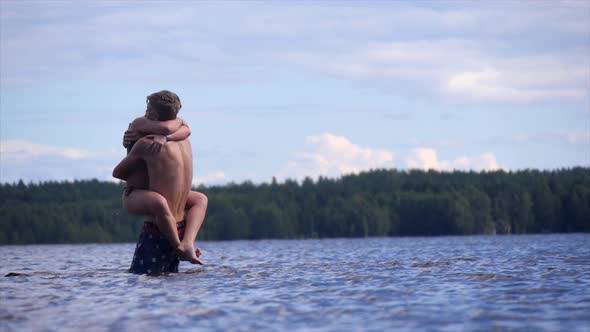 Young lovers hugging in a shallow lake.