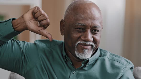 Portrait of Confident Elderly African American Man Indoors Looking at Camera Show Thumb Down
