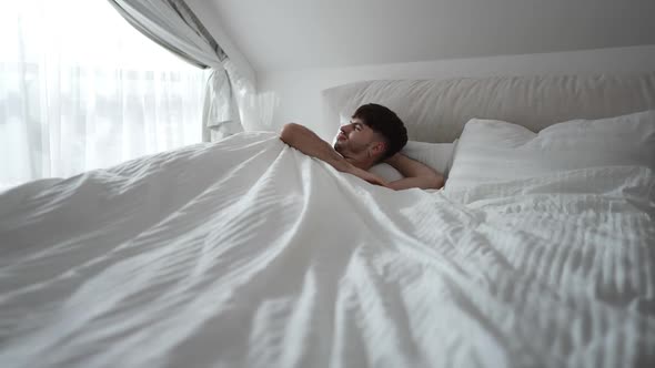 Wide Shot Sleeping Man Waking Up in Bedroom at Home in the Morning