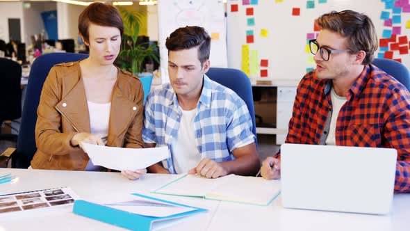 Graphic designer holding photo sample and interacting with colleagues