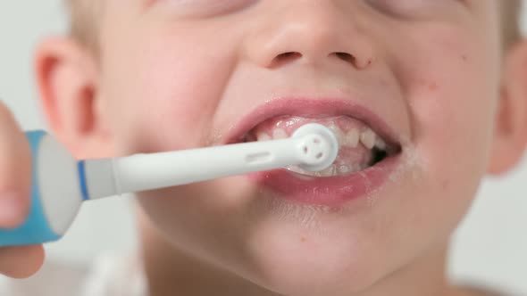 Portrait Happy Smiling Child Kid Boy Brushing Teeth with Electric Toothbrush on White Brick