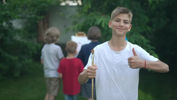 Portrait of Talented Teenage Boy Gesturing Thumb Up Smiling Looking at Camera