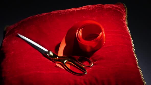 Golden Shears Fall on a Red Pillow for Ceremonies. Black. Rotation. Slow Motion