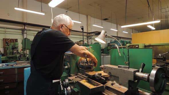 Caucasian Senior Old Man Worker Using Auto Lathe Machine Cutting Steel in Workshop