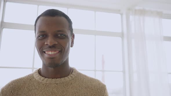 Closeup Portrait of African Black Man Looking at Camera and Smiling at Home Against Window