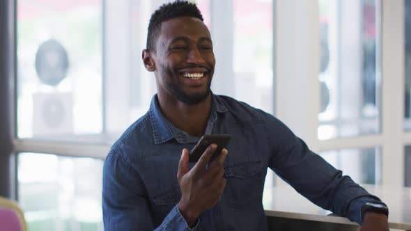 Smiling african american businessman talking on smartphone in cafe