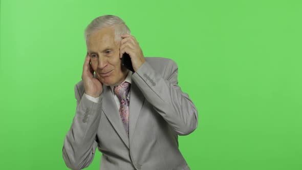 Handsome Elderly Businessman Talks on a Smartphone. Old Man in Suit