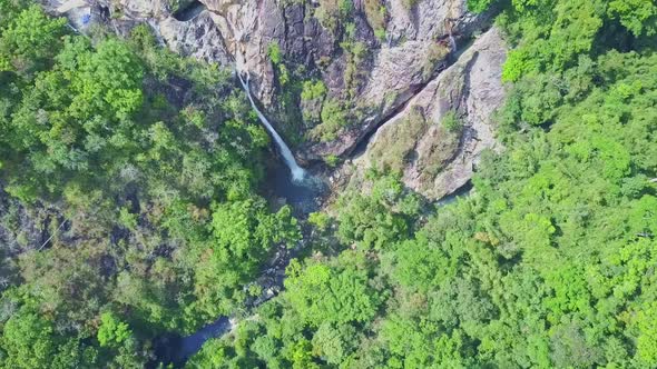 Drone Moves To High Waterfall Among Rocks in Jungle