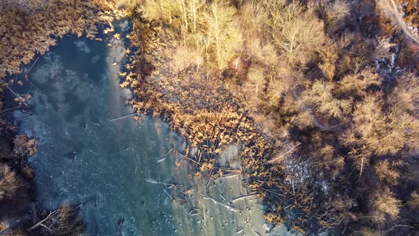 Aerial view on frozen wild lake in sunset forest