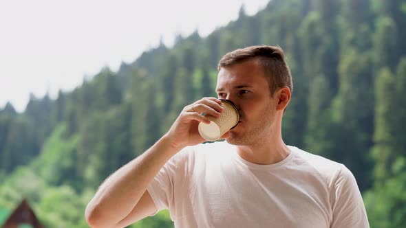 Portrait of Pleasant Guy Spending Time Enjoying Vacation and Drinking Coffee on Background of