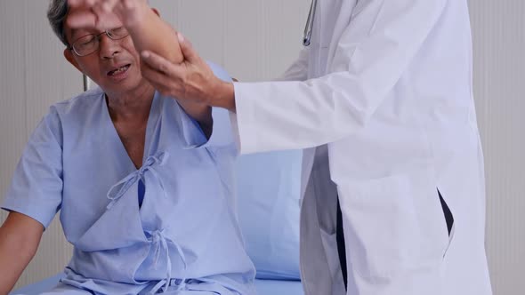 Doctor examining arm of elderly patient in clinic