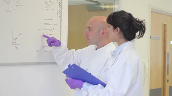 Scientist analyze and discuss research data on white board in science laboratory