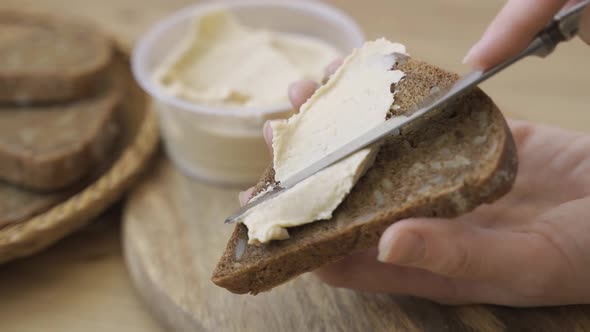 Close Up of Unrecognizable Female Hands are Spreading Butter on a Sandwich Using Butterknife