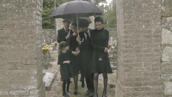 Mourners leaving graveyard in the rain