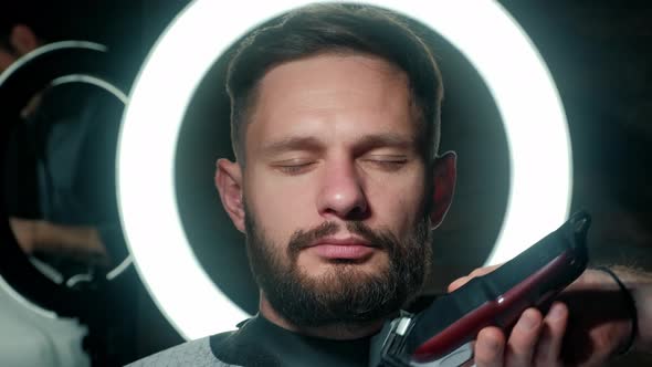 Barber Shaves the Client's Beard on a Chair. Beard Haircut. Barber To Shave a Beard with an Electric