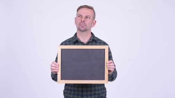 Portrait of Happy Blonde Hipster Man Thinking While Holding Blackboard