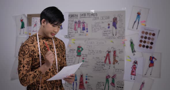 Asian clothing designer working in his office, creating a new clothes collection