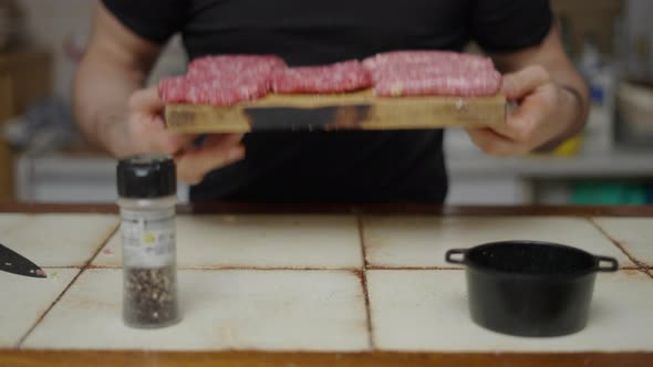 Chef Showing Seasoned Burgers and Sausages in Cutting Board in Slow Motion