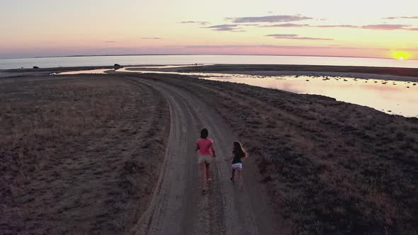 Two Sisters Play on Wild Sandy Terrain