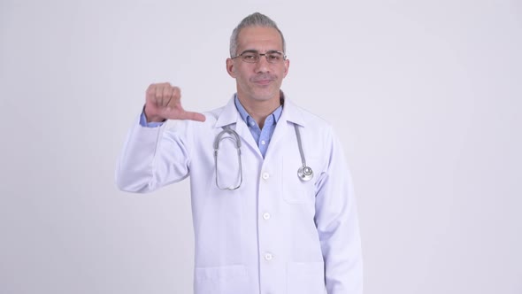 Stressed Persian Man Doctor Giving Thumbs Down Against White Background