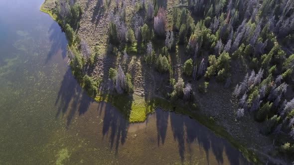 Flying over lake tilting up to view horizon over forest